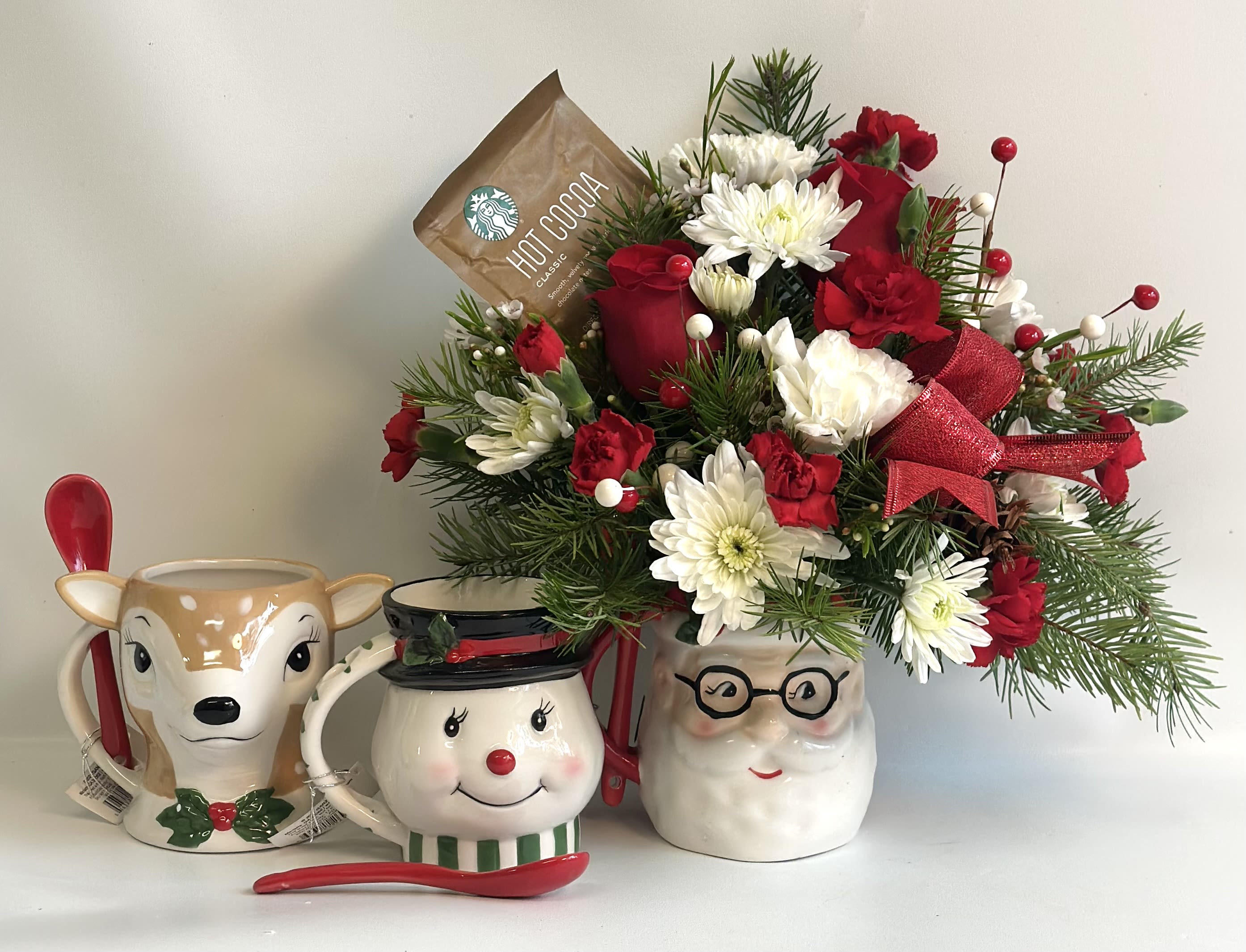 Holiday floral arrangement in a Santa mug with red and white flowers