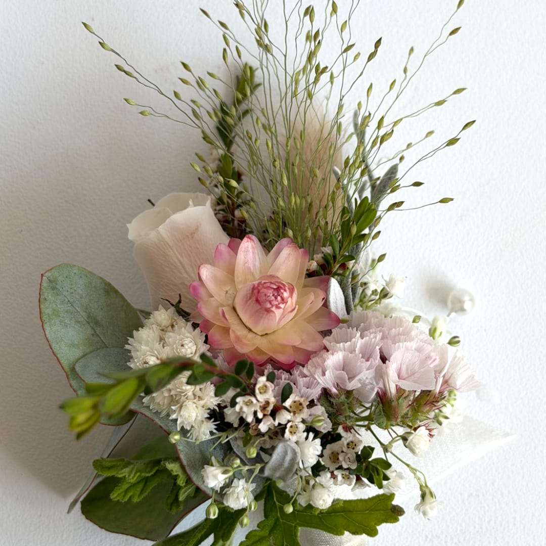 Pink and white floral arrangement with a large central bloom and airy grasses