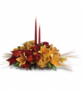 Graceful Glow Centerpiece - Delightful red roses, orange asiatic lilies, orange and bronze chrysanthemums, and burgundy ribbon surround two elegant taper candles. Accents of natural wheat make this gift wildly festive! Approximately 26 W x 17 1/2 H