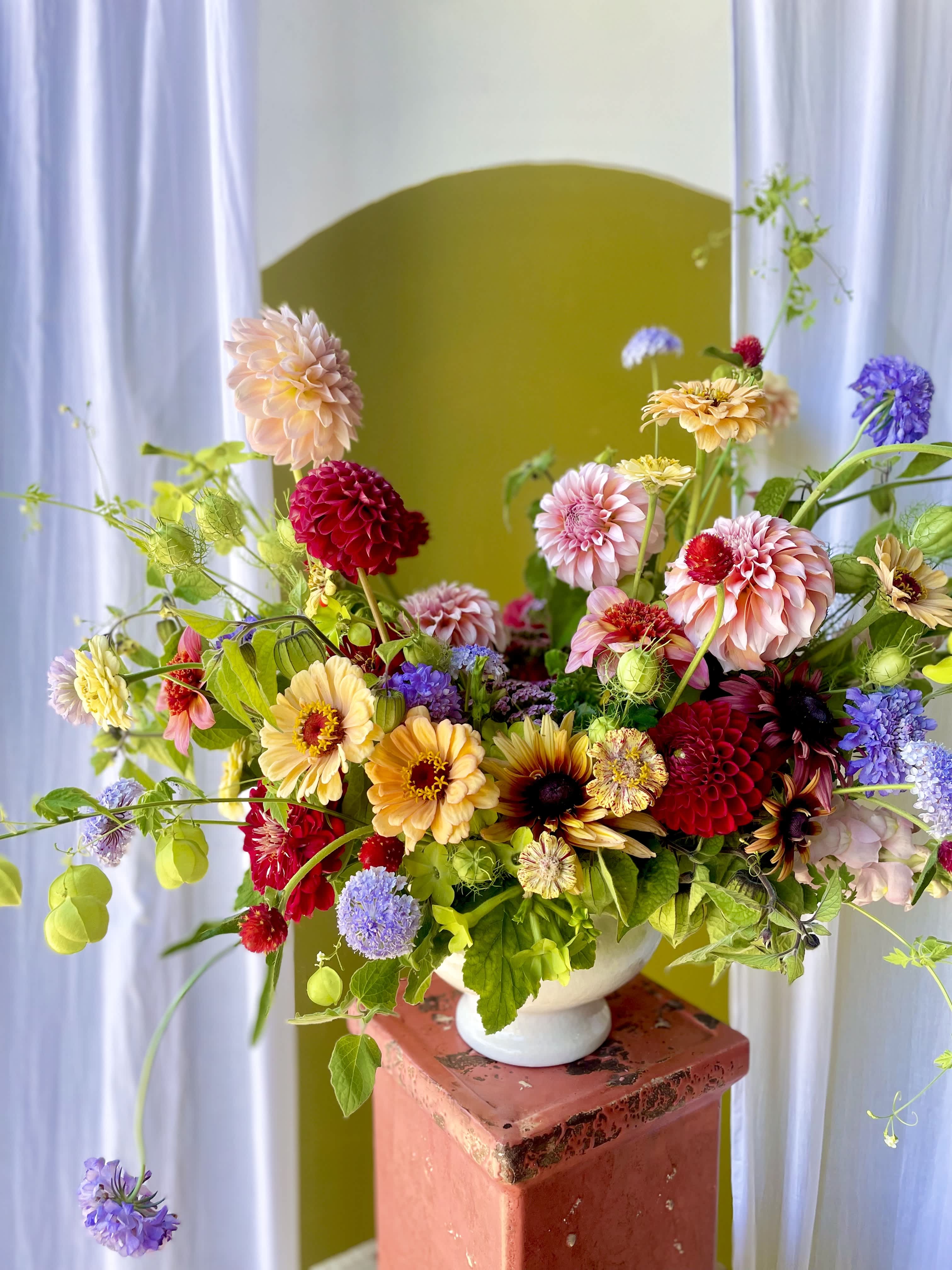 Colorful mixed flower arrangement in a white pedestal vase