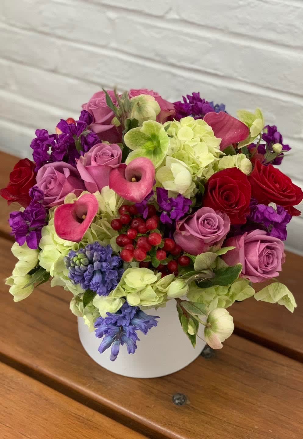 Mixed bouquet of pink roses, calla lilies, and hydrangeas in a white vase