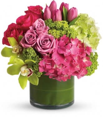 Pink and red flower arrangement in a green glass vase