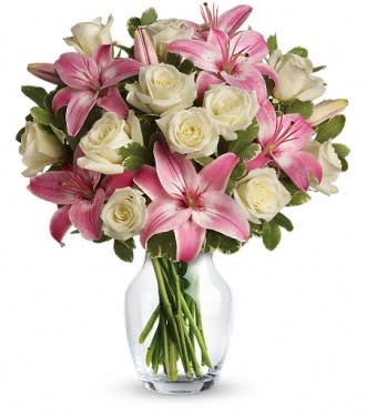 Pink lilies and white roses arranged in a clear glass vase