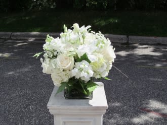 White floral arrangement in a square vase on a pedestal