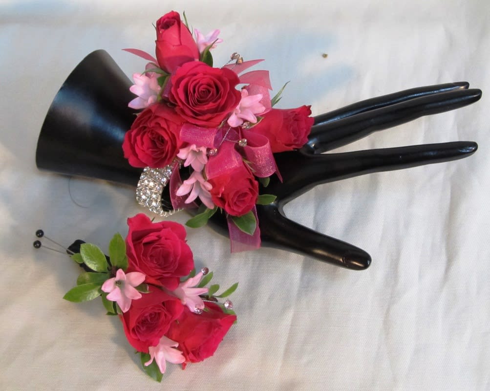 Pink rose corsage and boutonniere with ribbon on a black display hand