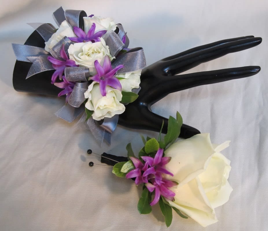 Two white rose boutonnieres with purple accents and silver ribbon