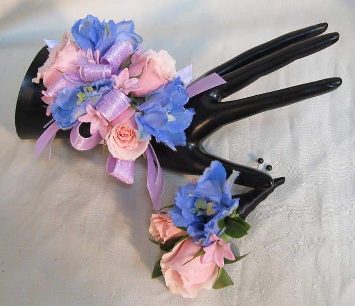 Two floral corsages with pink and blue flowers on black display hands