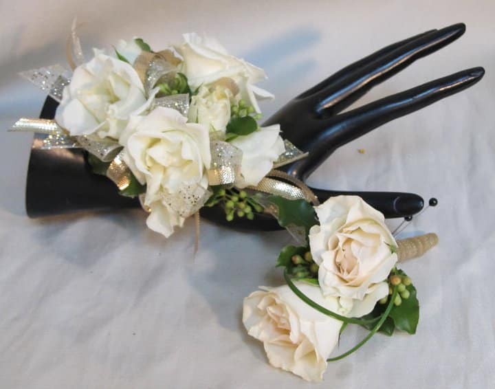 White rose corsage with ribbon on a black mannequin hand