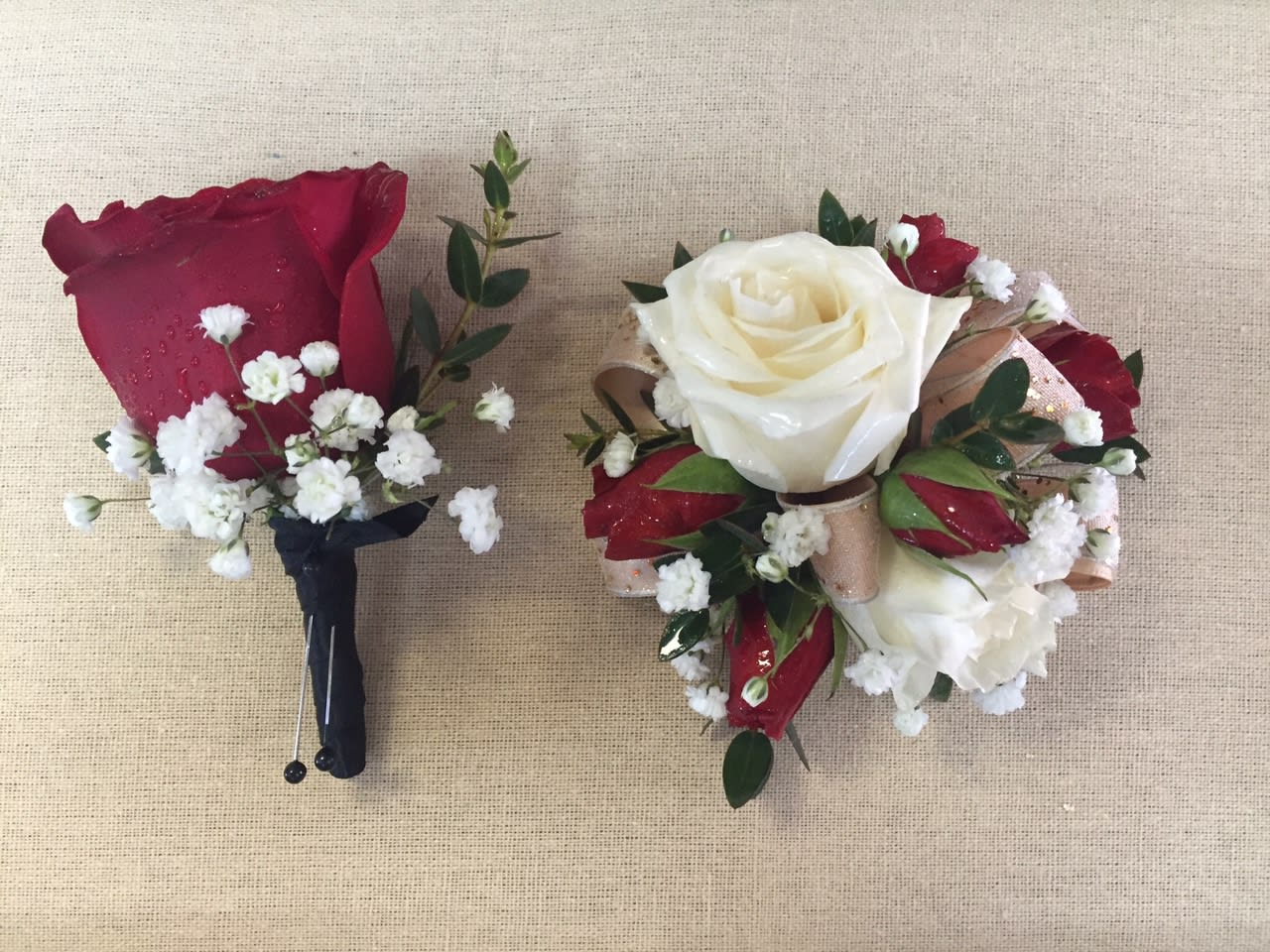 Two rose boutonnieres with baby's breath on a burlap background