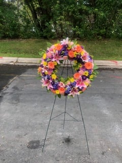 Colorful floral wreath on a metal stand outdoors