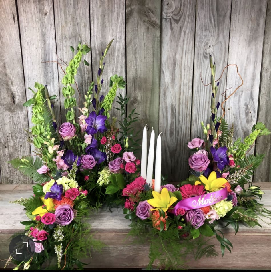 Colorful floral arrangement with candles and a pink ribbon