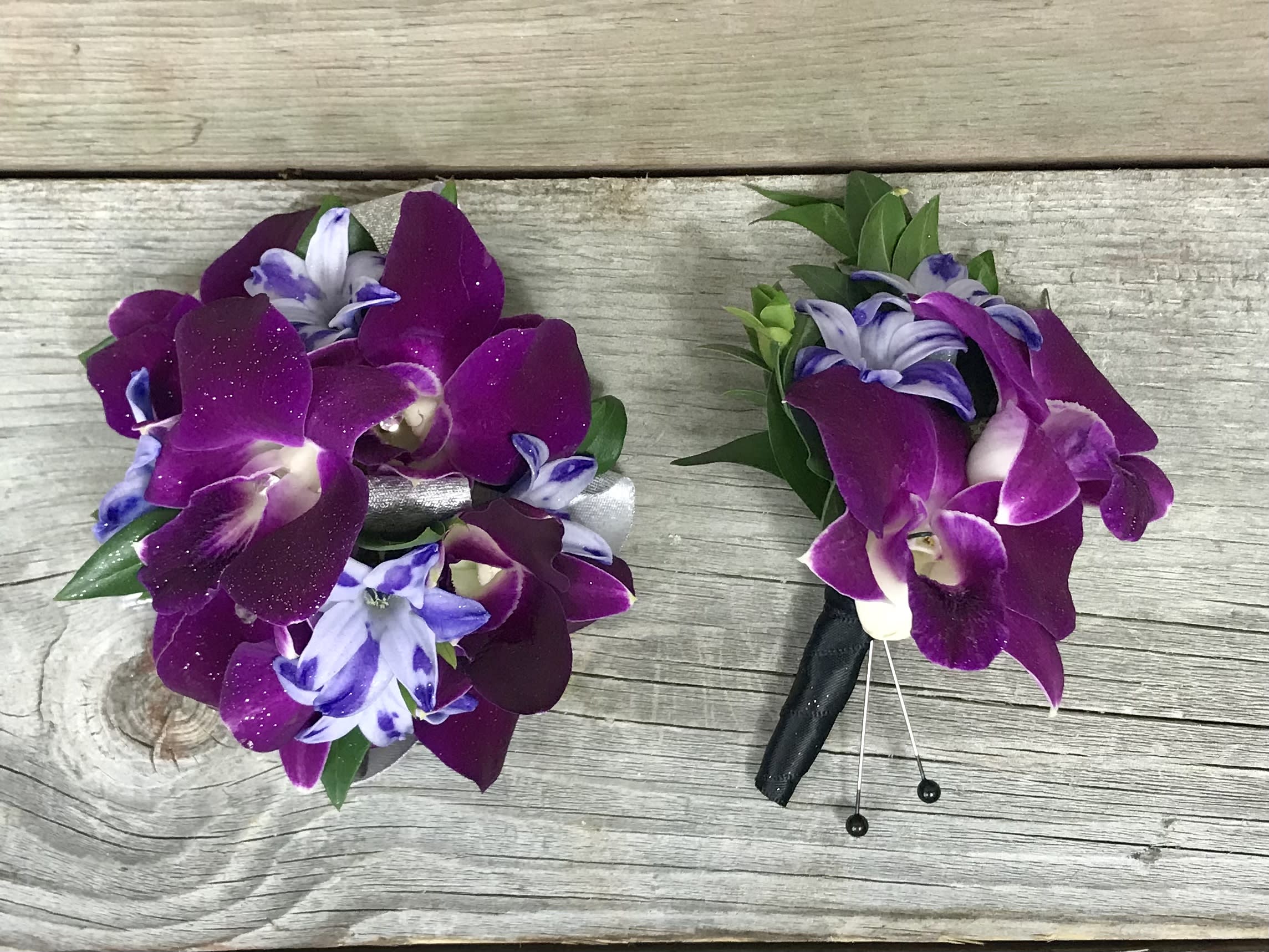 Two purple orchid boutonnieres on a wooden surface
