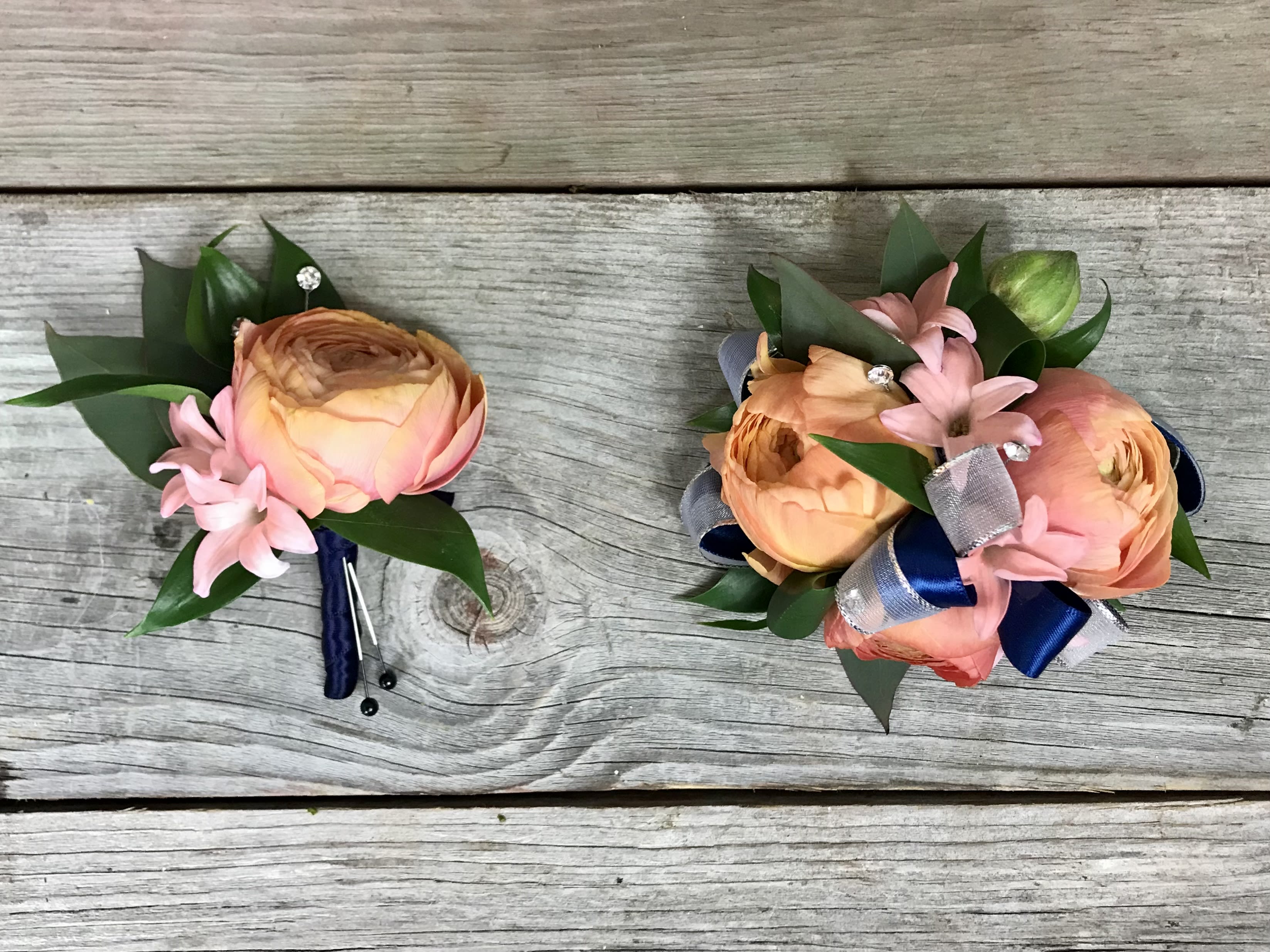 Two small floral boutonnieres with peach blooms and pink accents