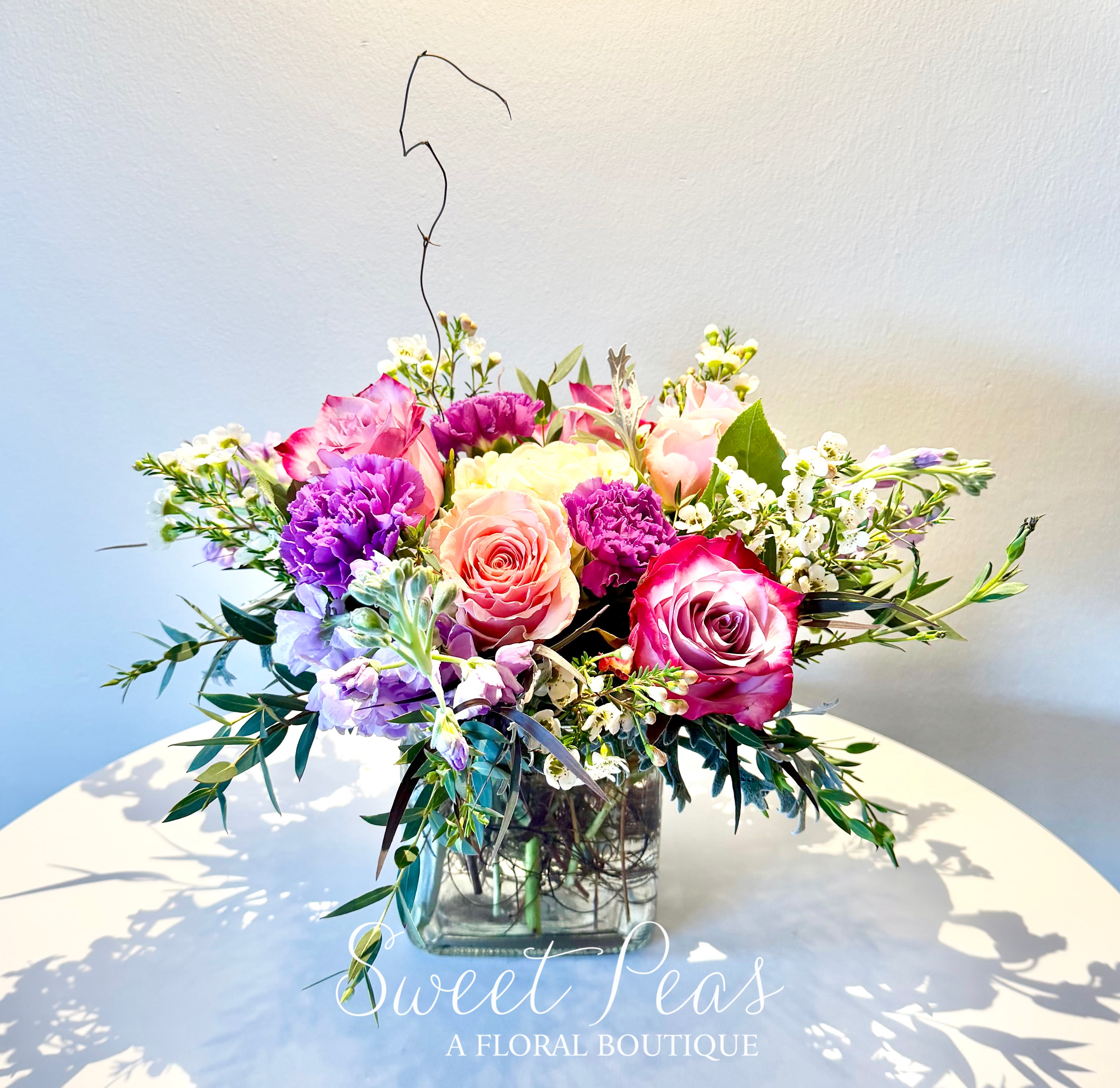 Mixed pink and purple bouquet in a square glass vase