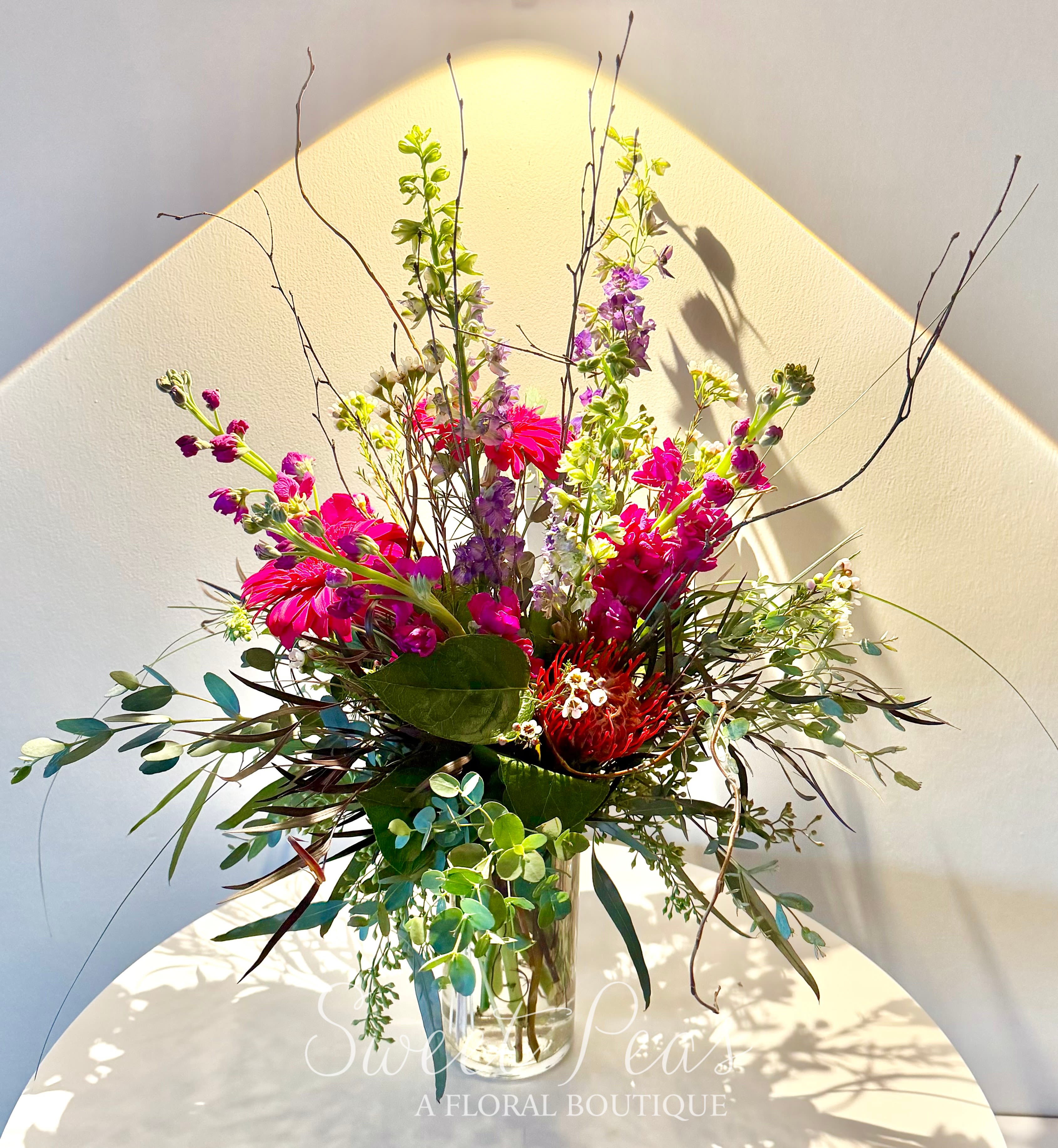 Tall mixed bouquet in a clear glass vase with bright pink and purple blooms
