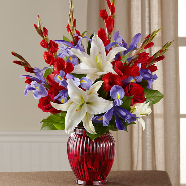 Red, white, and purple floral arrangement in a red glass vase