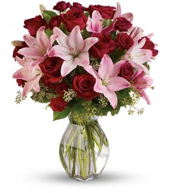 Bouquet of red roses and pink lilies in a clear glass vase