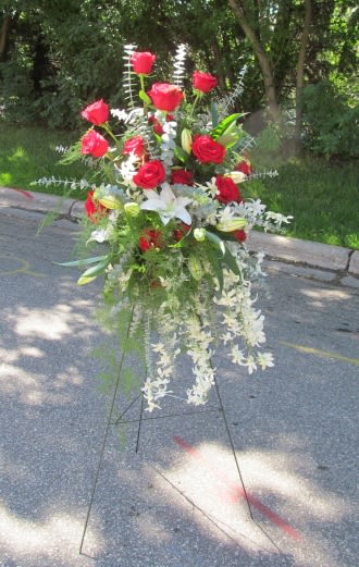 Tall floral spray with red roses, white lilies, and cascading white flowers