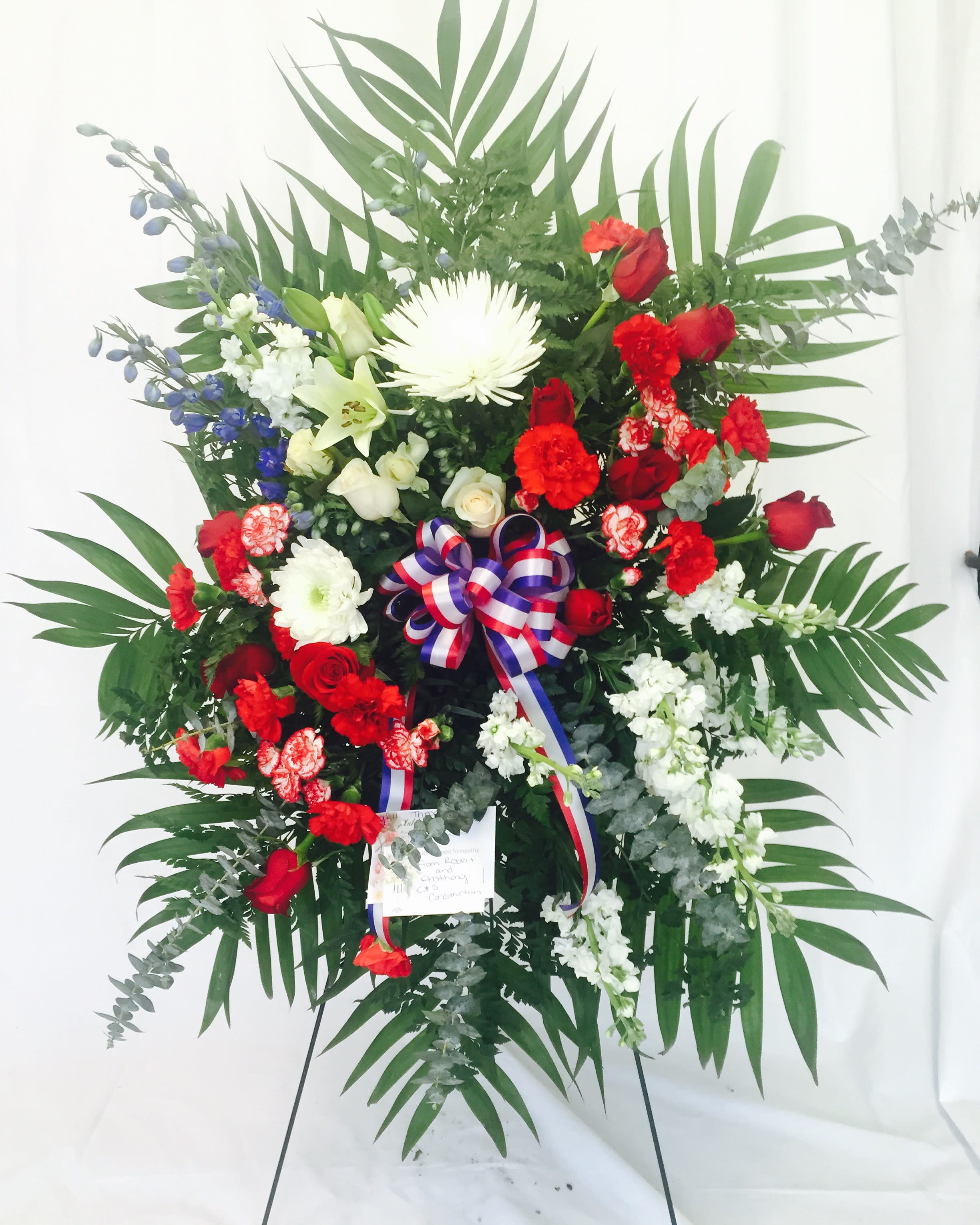 Large standing floral spray with red, white, and blue flowers on an easel