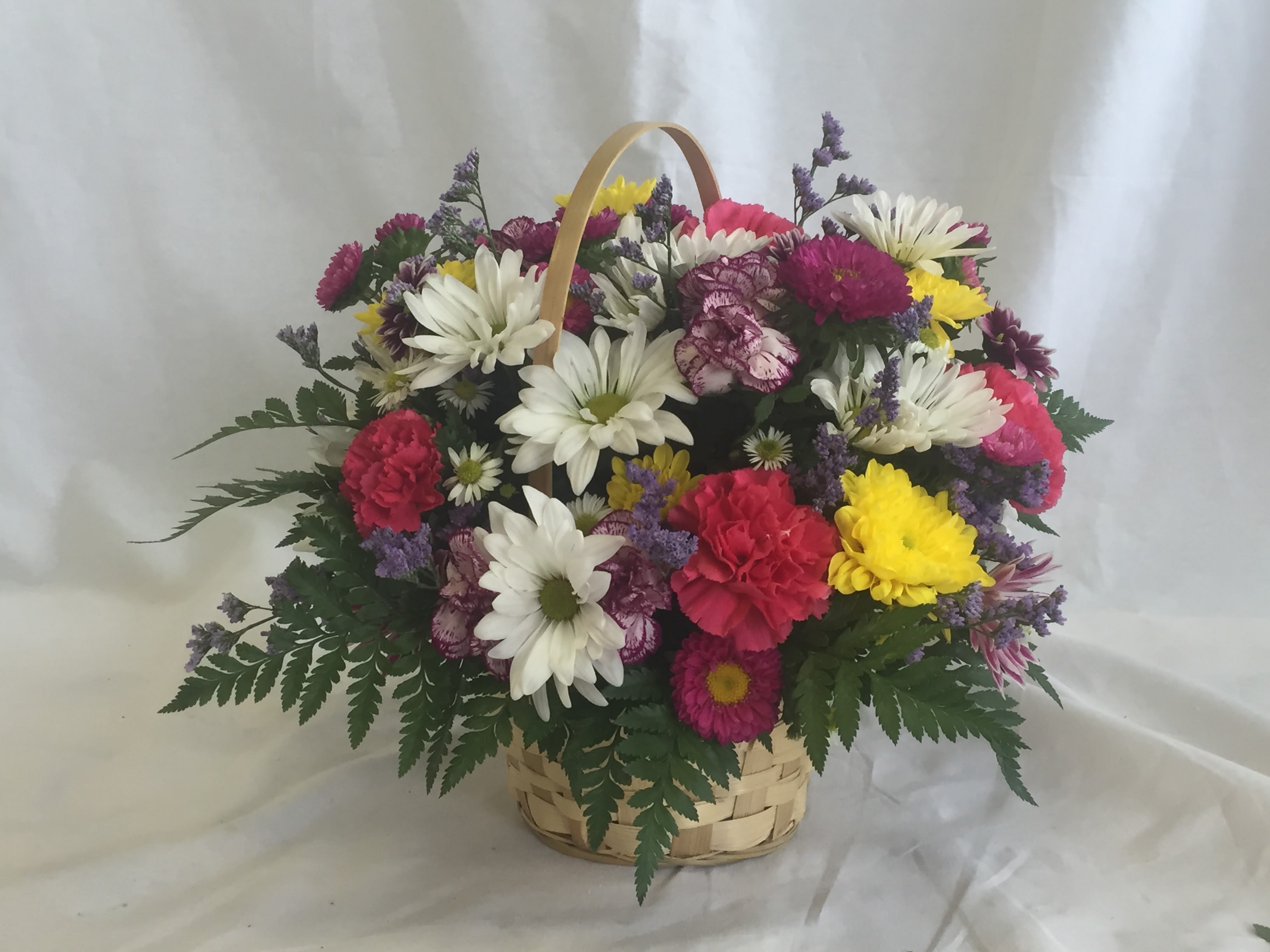 Mixed bouquet of daisies, carnations, and chrysanthemums in a basket