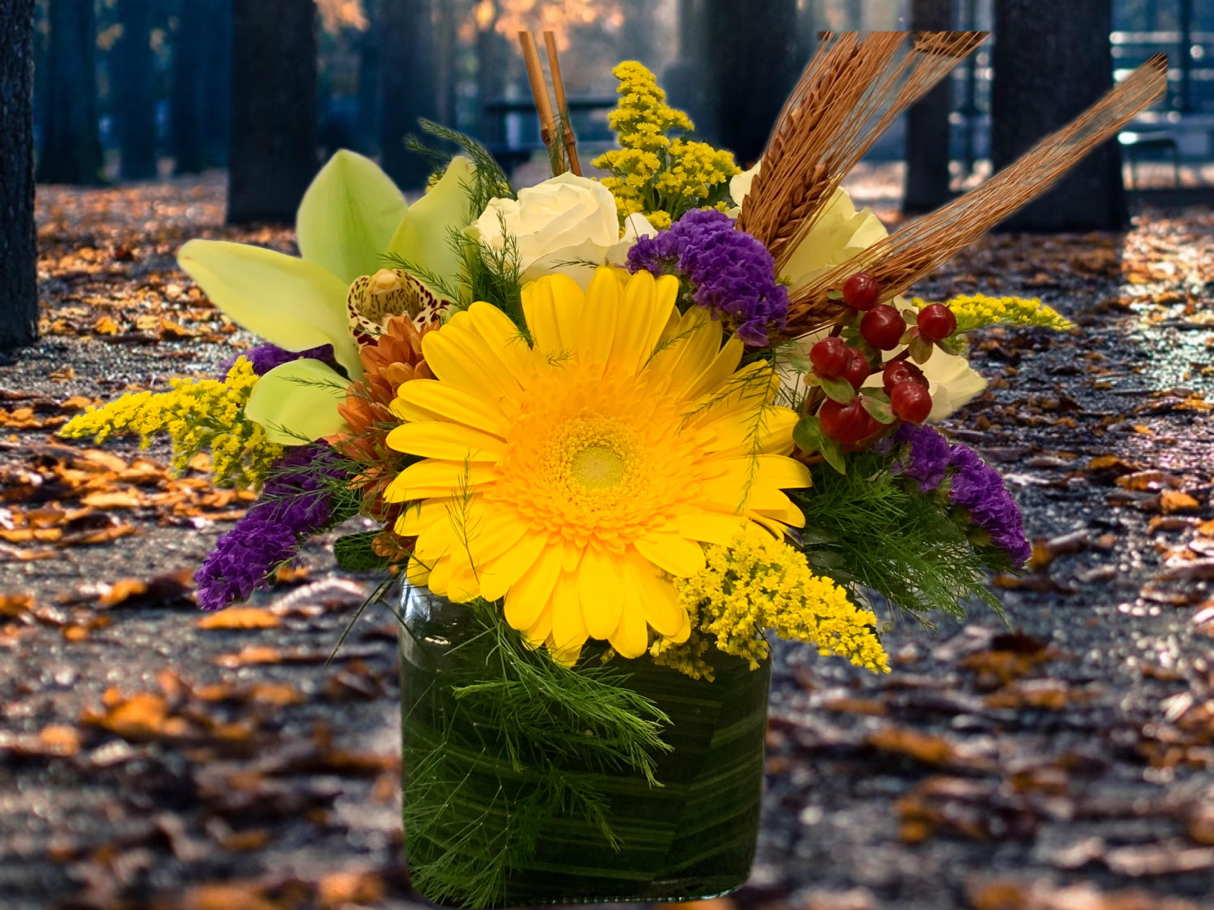 Yellow gerbera bouquet in a glass vase with purple accents