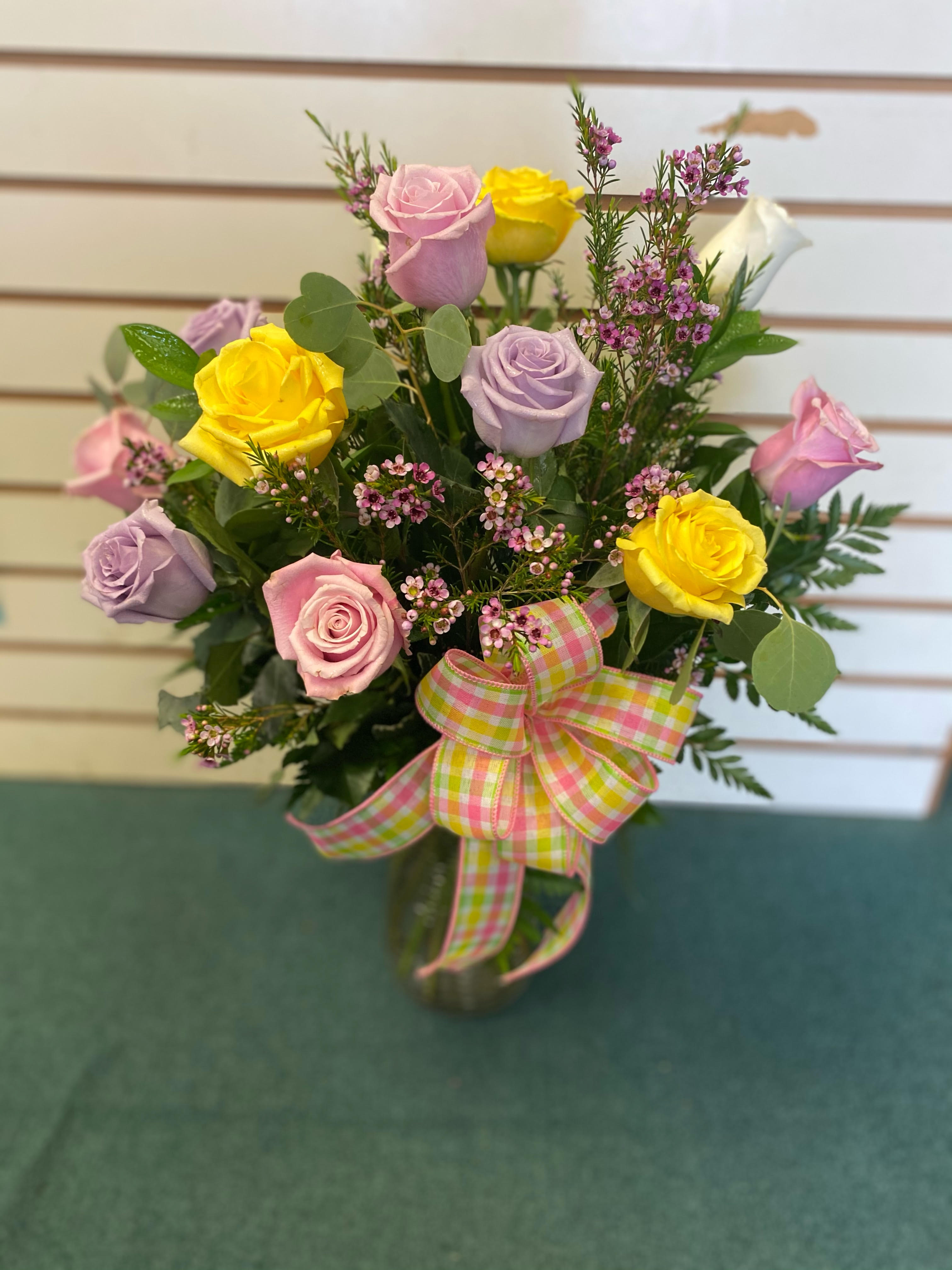 Bouquet of pink, yellow, and lavender roses with a plaid ribbon