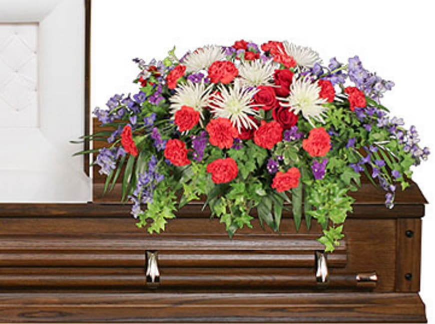 Large floral spray on a wooden casket with red, white, and purple flowers