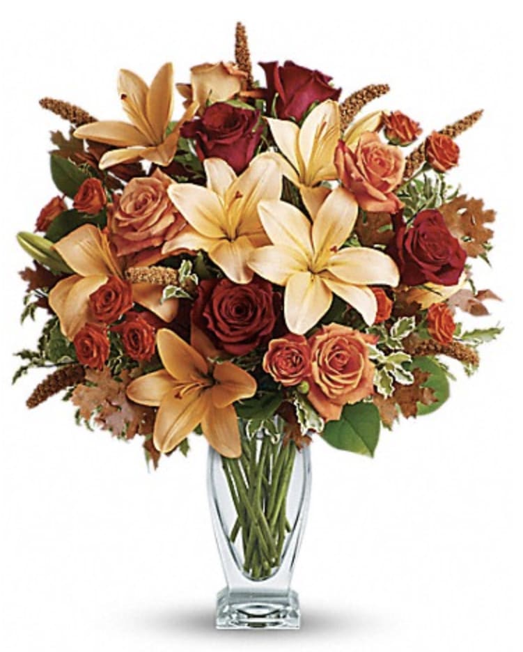 Teleflora's Fall Fantasia - Roses, lilies and oak leaves create a fantasy of fall flowers. Send this tall, elegant arrangement to wish someone a happy autumn or joyous Thanksgiving. The warm color palette and Couture Vase make a stylish seasonal statement.
