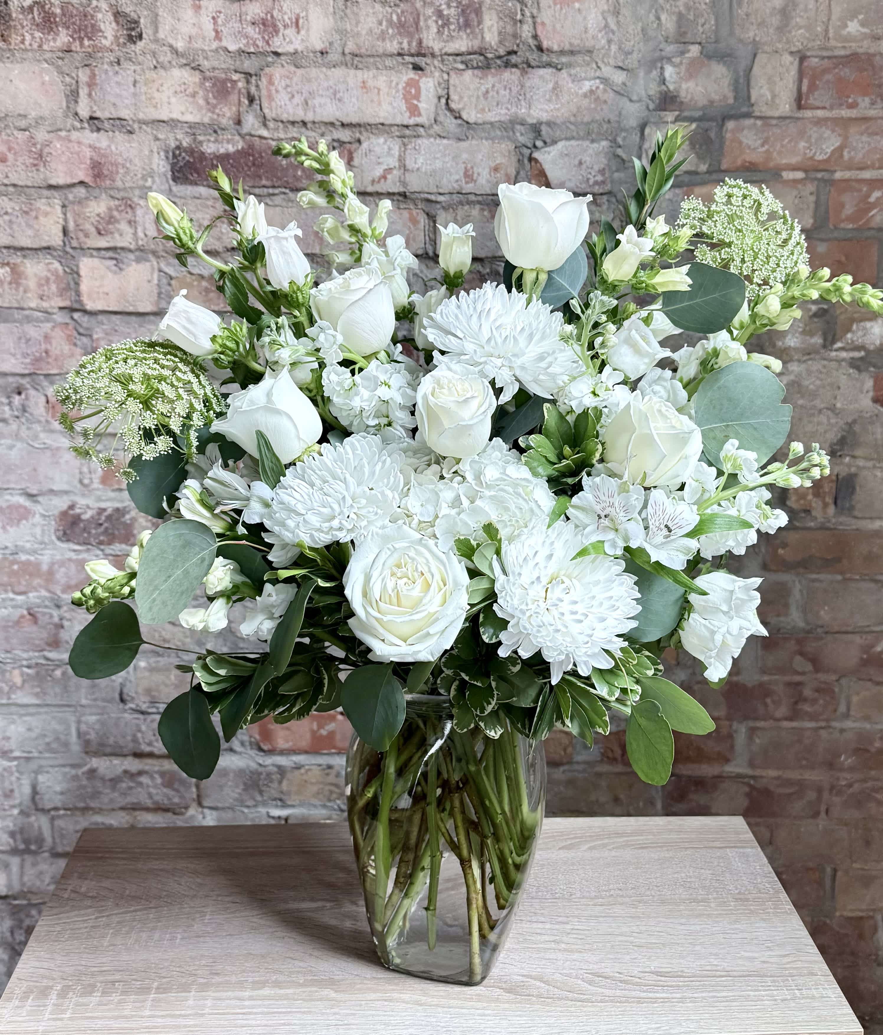 White floral arrangement in a clear glass vase on a table