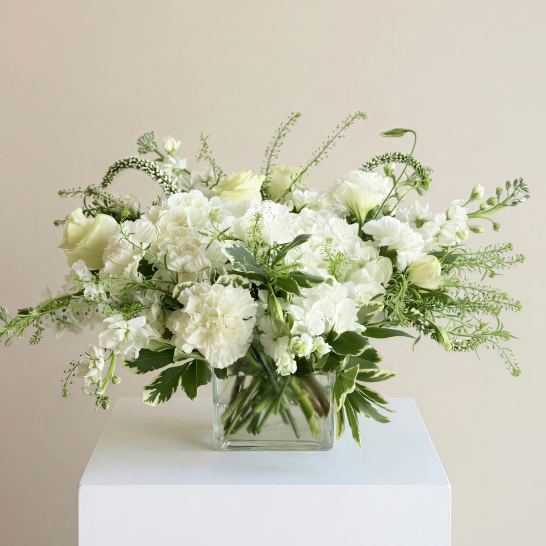 White floral arrangement in a clear square vase
