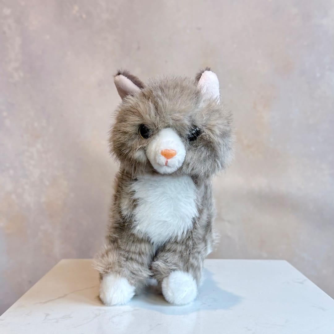 Small gray-and-white plush cat sitting on a tabletop