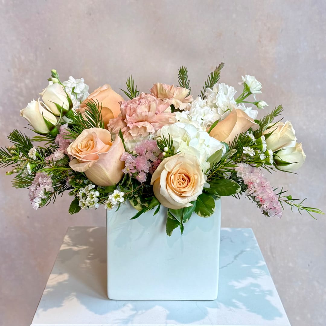 Peach and white roses with pink carnations in a white vase