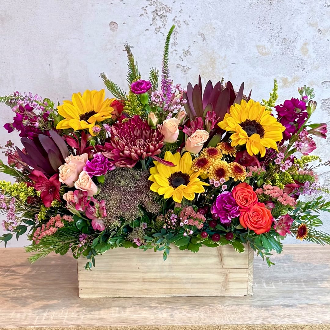 Mixed bouquet in a wooden box with sunflowers, roses, and chrysanthemums