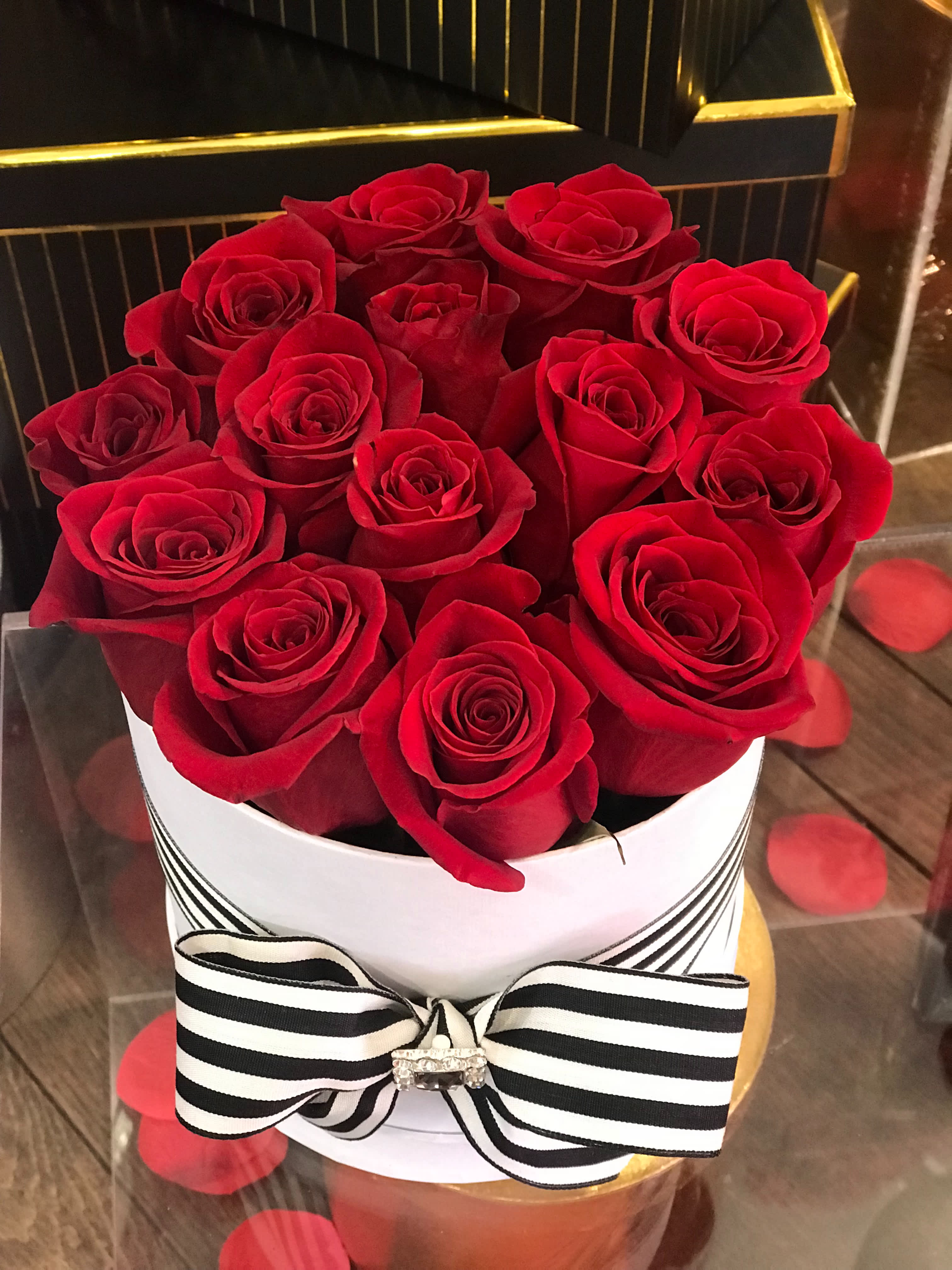 Red roses arranged in a white hat box with a black-and-white ribbon