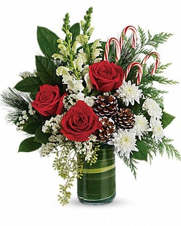 Red roses and white flowers in a green glass vase with candy canes and pinecones