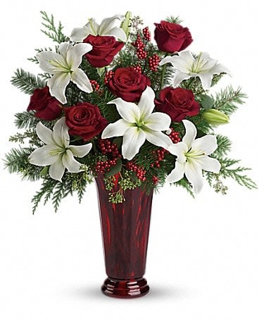 Holiday Magic - With beautiful red roses and brilliant white lilies delivered in a dramatic tall ruby vase, this dazzling holiday arrangement casts an enchanting spell. A step up from the traditional, its effect is nothing less than magical. White asiatic lilies, red roses, fir, cedar and eucalyptus create the perfect holiday bouquet, especially when delivered in a stunning ruby red roman column vase.