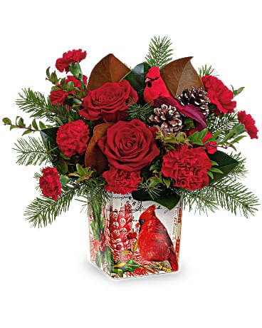 Teleflora's Joyful Cardinal Bouquet - Capture the beauty of a winter forest with this vintage-inspired cube vase, decorated with a crimson cardinal and brimming with radiant roses and fresh holiday greens. Add a candle to the cube next Christmas! Red roses, red carnations, miniature red carnations and red huckleberry are arranged with magnolia leaves and douglas fir. Delivered in a Cardinal Cheer Cube.