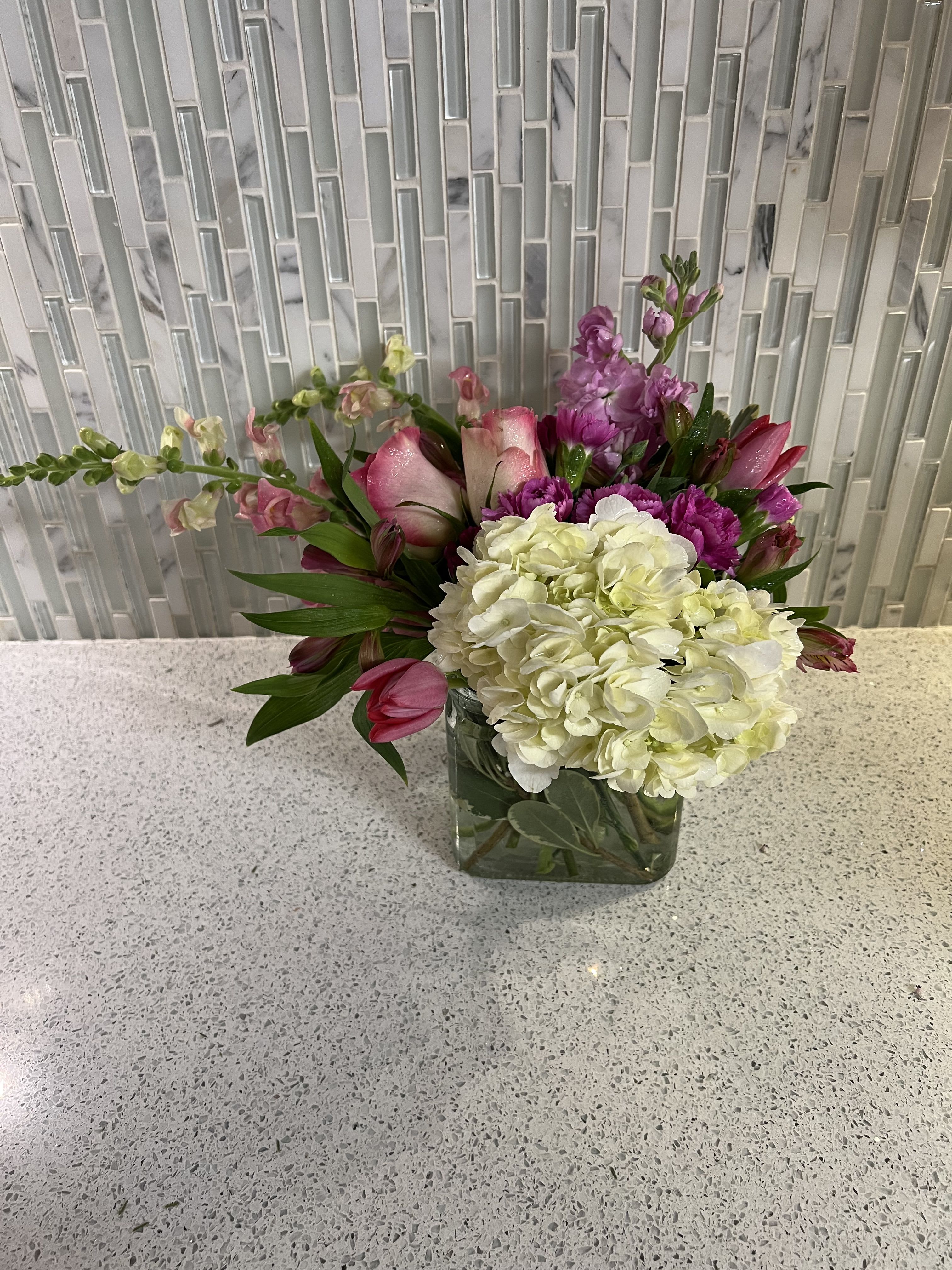 Pink and white floral arrangement in a square glass vase