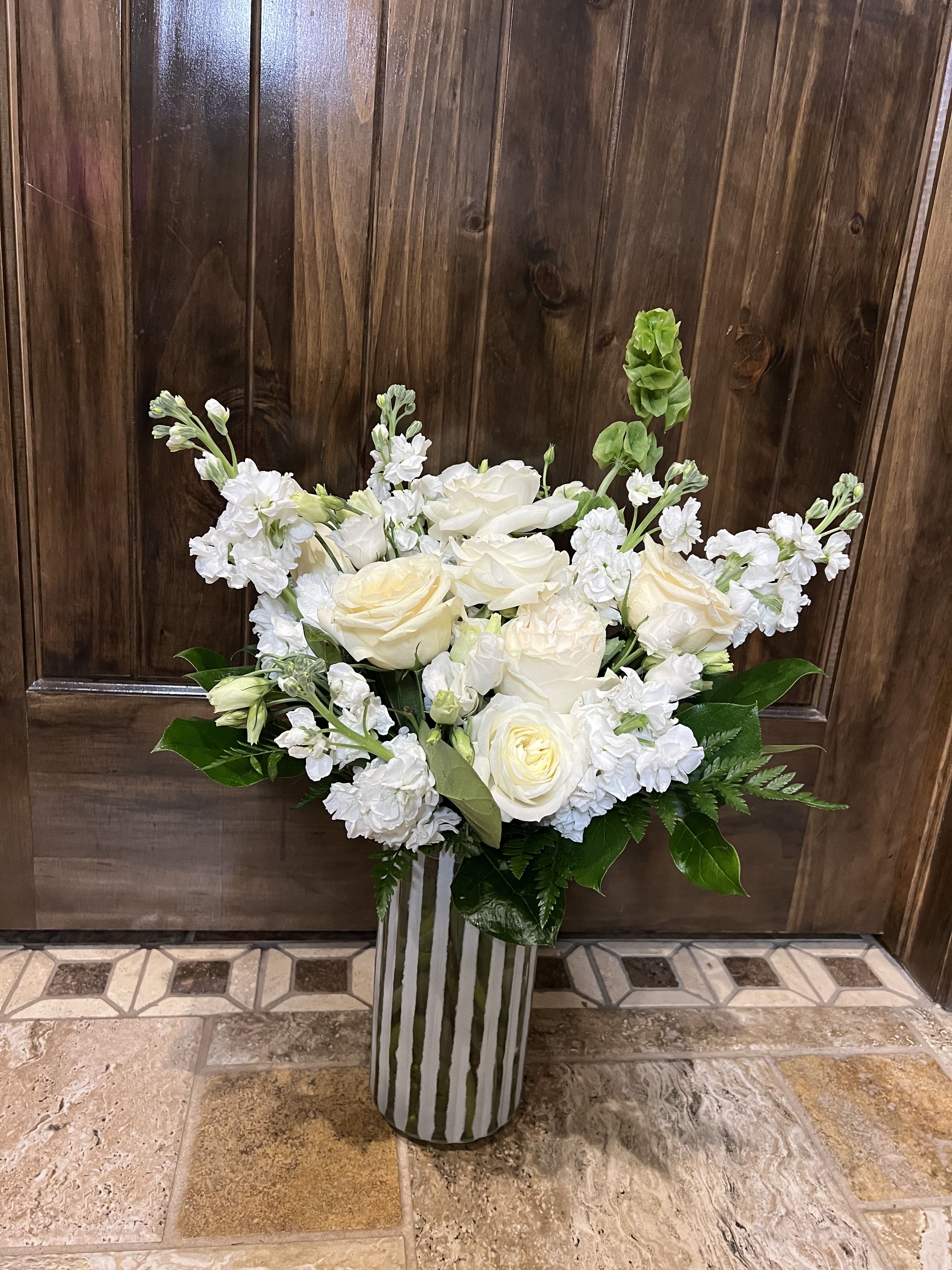 White roses and stock arranged in a striped vase