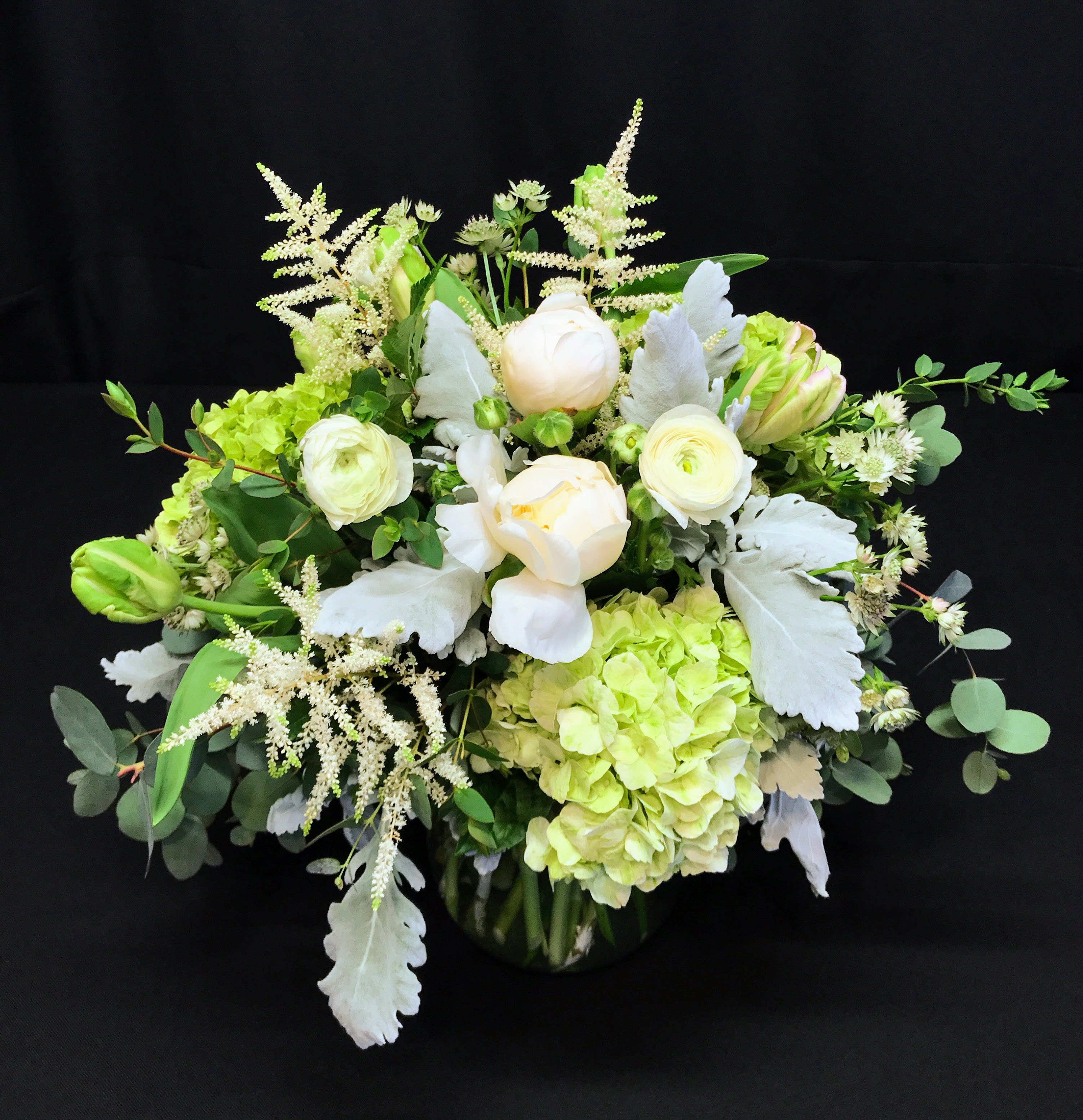 Round white centerpiece with soft green grey - Beautiful soft centerpiece in shades of white, ivory, light green and grey-blue (foliage). Premium flowers and greenery. Faces all directions for best viewing down low on a coffee table or dining table.  Exquisite selection for sympathy to the family's home.