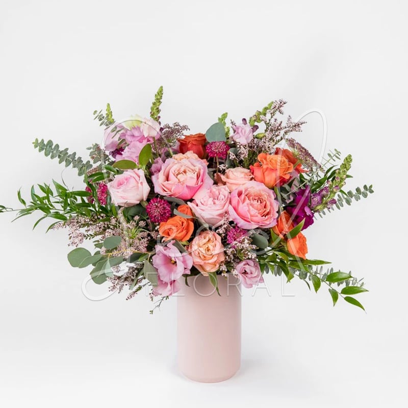 Pink and orange rose bouquet in a tall blush vase