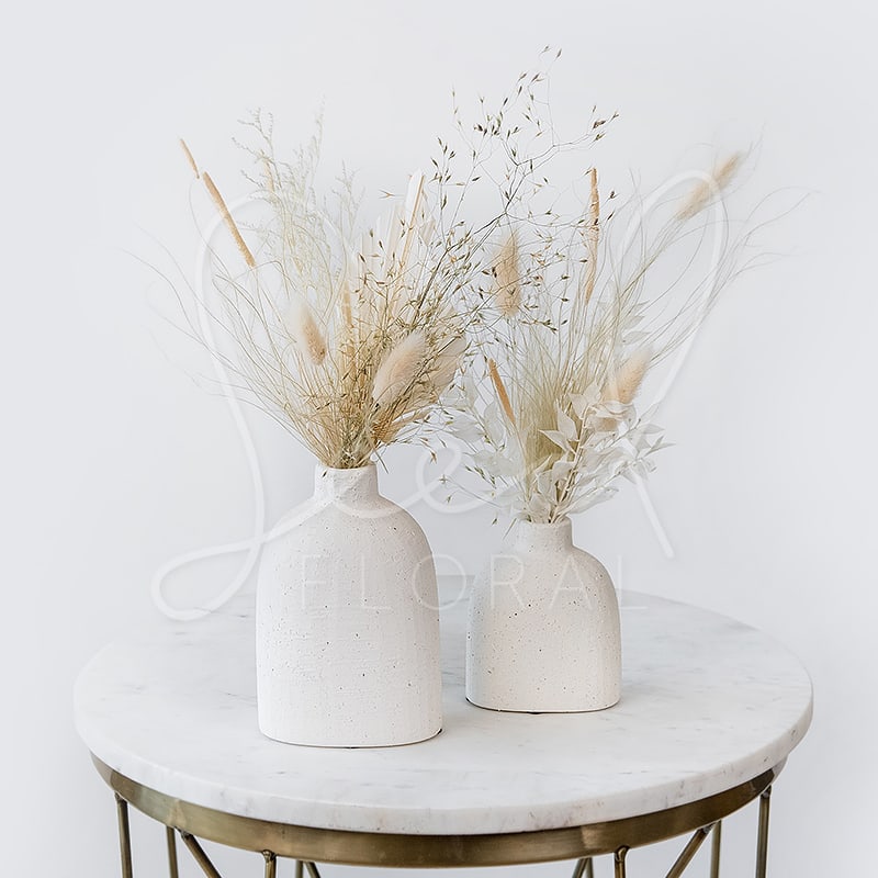 Two white ceramic vases with dried grasses and beige stems