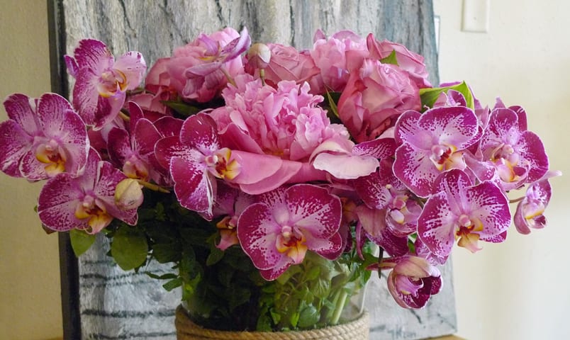 Pink orchids and roses arranged in a glass vase