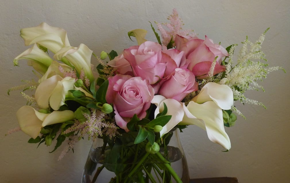 Pink roses and white calla lilies in a glass vase