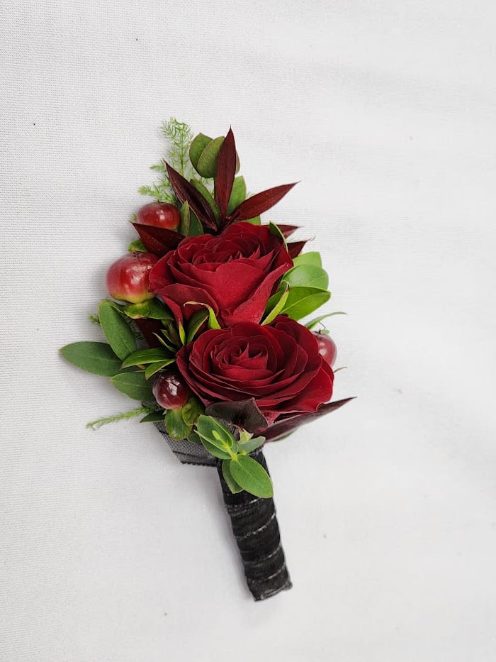 Red rose boutonniere with berries and greenery on a black wrapped stem