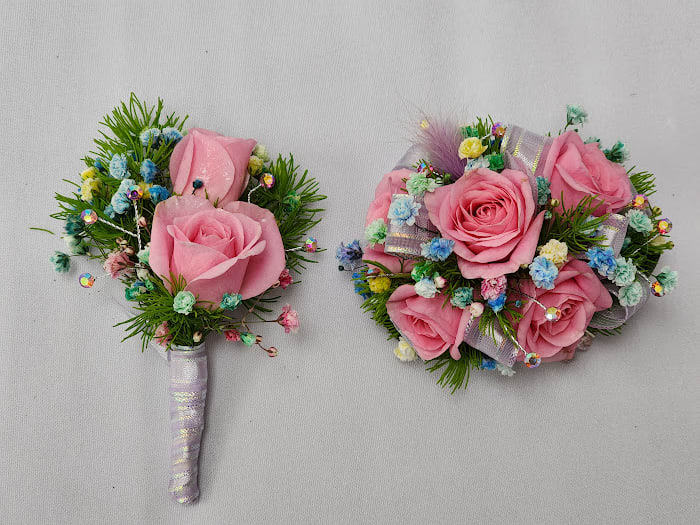 Candyland Boutonniere and Wristlet Set - Select this wristlet corsage and boutonniere set that features pink spray roses, rainbow babies breathe, and accents of iridescent rhinestones and purple iridescent ribbon. The wristlet will come on a clear and light pink beaded wristband. The boutonniere will come with two black pins to pin on their lapel or shirt.