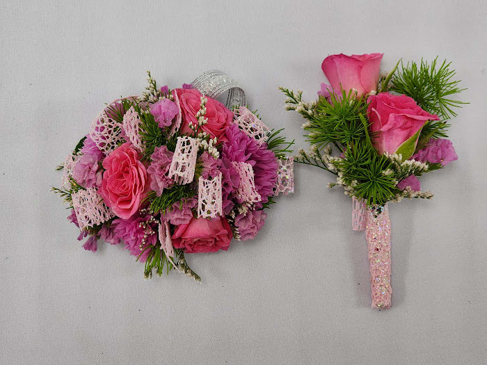 Barbie Boutonniere and Wristlet Set - Select this adorably pink boutonniere and corsage set featuring spray roses, cornflower, statice, and misty. The wristlet corsage will come on a standard grey wristband that is elastic. The boutonniere will come with two black pins to pin on their lapel or shirt.