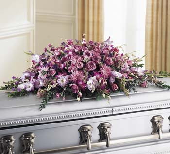 Lavender and pink mixed-flower casket spray in a long cascading design on a silver casket.