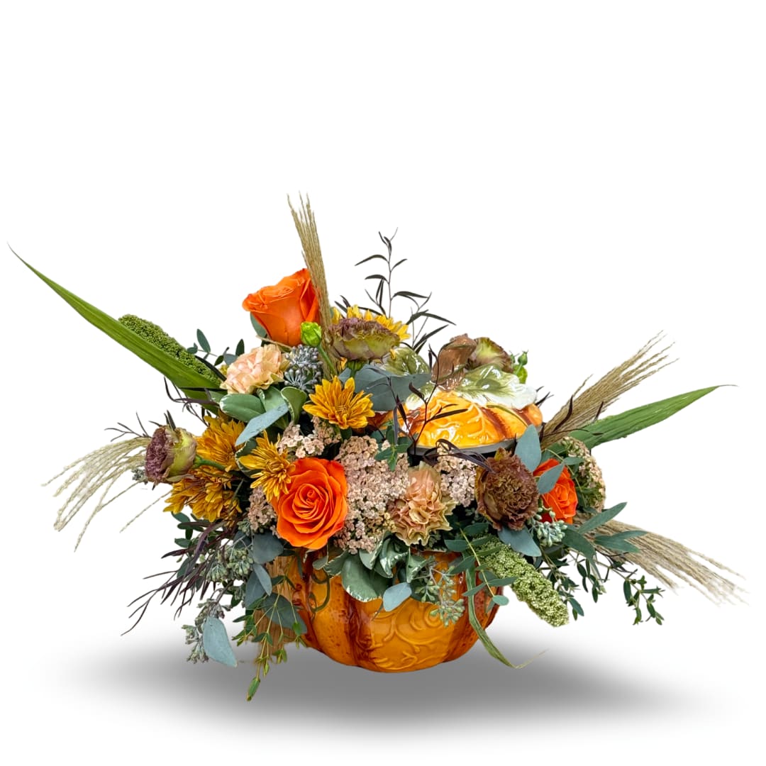 Orange floral arrangement in a carved pumpkin container with mixed blooms