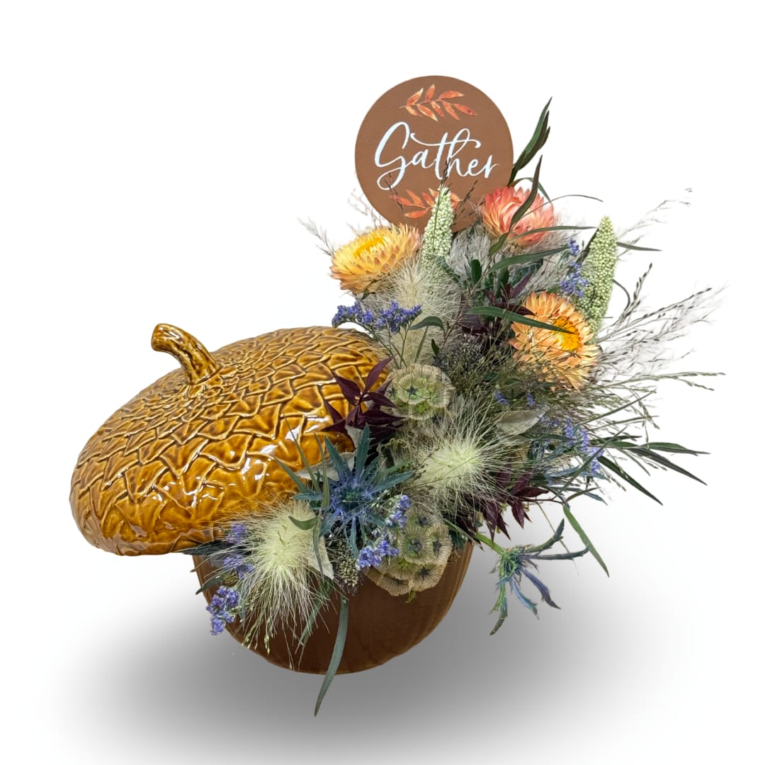 Autumn floral arrangement in a pumpkin container with a "Gather" sign